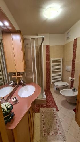 a bathroom with two sinks and a shower and a toilet at Appartamento Cesa Lamar in Canazei