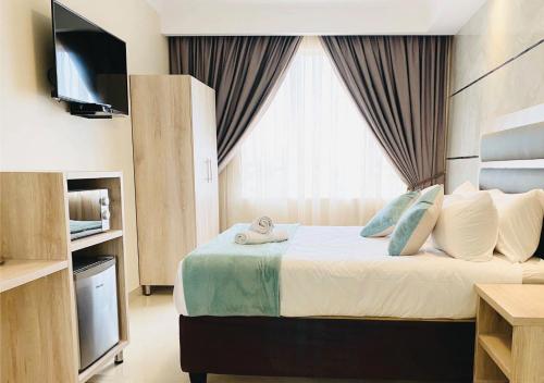ein Hotelzimmer mit einem Bett und einem TV in der Unterkunft Bayside Hotel 116 West Street in Durban