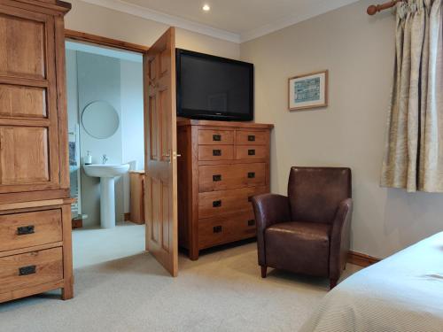 a bedroom with a television on a dresser and a chair at Nant Gloyw Oswestry in Oswestry