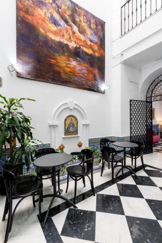 a room with tables and chairs and a large painting on the wall at Cool Sevilla Hotel in Seville