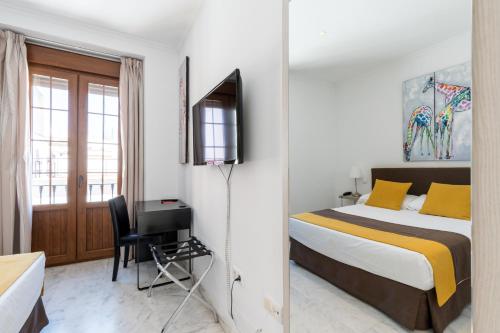 a bedroom with a bed and a desk and a television at Cool Sevilla Hotel in Seville