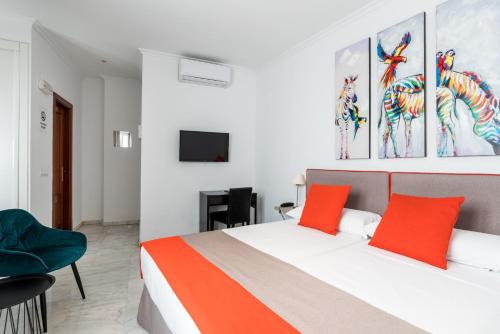 a bedroom with a bed with orange pillows and a tv at Cool Sevilla Hotel in Seville