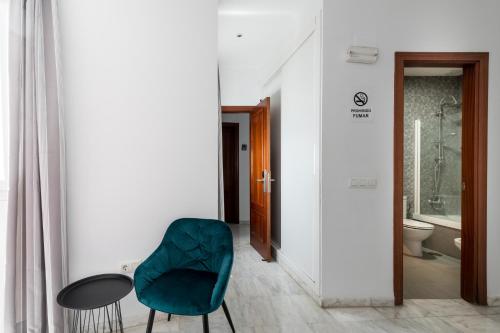 a room with a green chair and a table at Cool Sevilla Hotel in Seville