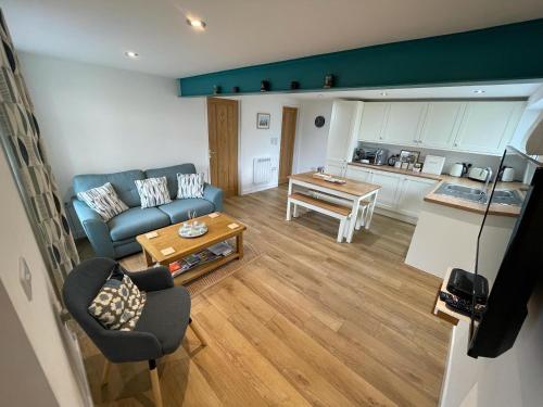 un soggiorno con divano blu e una cucina di Lovely ground floor apartment in quiet village a Exeter