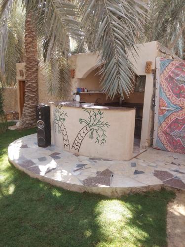 a house with a table with a palm tree painted on it at Nour El Waha Hotel in Siwa
