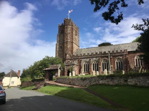 an old stone building with a tower on a street at Lovely ground floor apartment in quiet village in Exeter