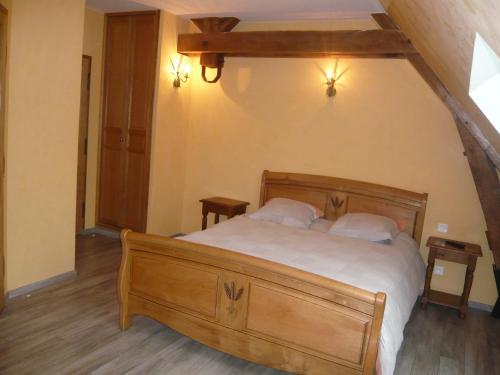 a bedroom with a large wooden bed with two pillows at Domaine d'Auxonnettes Chambres d'Hôtes et Gîtes in Saint-Fargeau-Ponthierry
