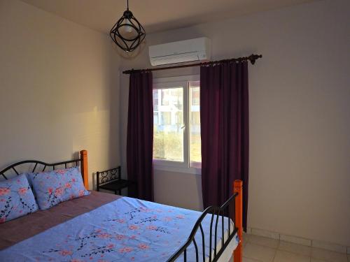 a bedroom with a bed with purple curtains and a window at Ertunalp Apartment in Mağusa
