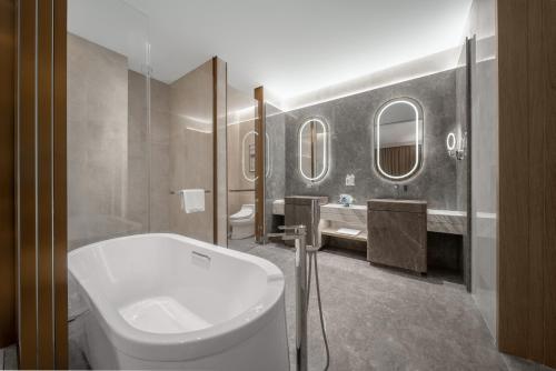 ein Bad mit einem WC, einem Waschbecken und Spiegeln in der Unterkunft Holiday Inn Fu'an in Fu'an