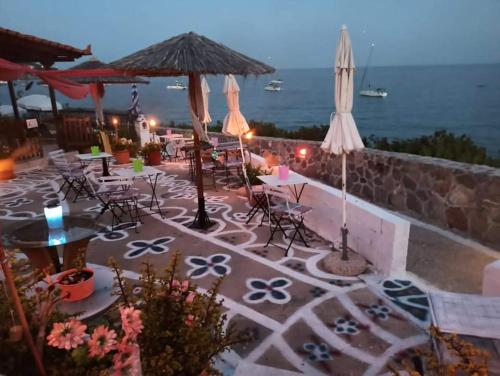 a patio with tables and chairs and an umbrella at Anatoli Hotel in Agia Marina Aegina