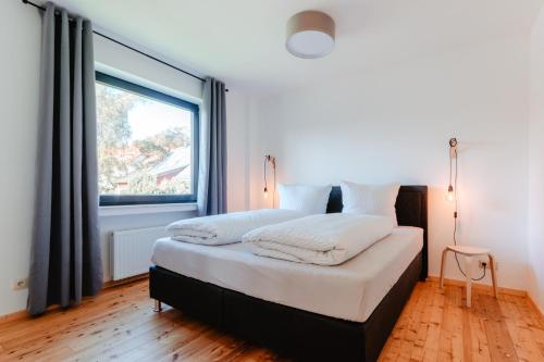 une chambre avec un lit et une grande fenêtre dans l'établissement Granetal.Quartier, à Hahnenklee