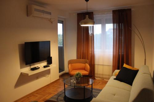 a living room with a white couch and a tv at Summit rooms , Parking in garage in Niš