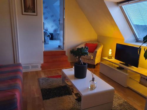ein Wohnzimmer mit einem TV und einem Tisch in der Unterkunft Joelle et Hans B&B in Hôpital-Camfrout