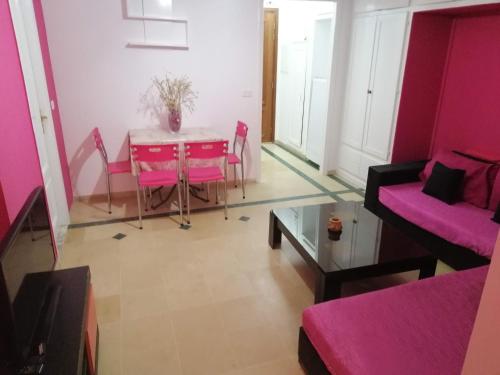 a living room with pink furniture and a table at résidence les jardins in El Aouina