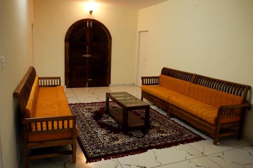 a living room with two couches and a table at Green Garden Holiday Home Wayanad in Vythiri