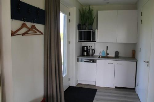 uma cozinha com armários brancos, um lavatório e uma janela em BakBoord em Grou