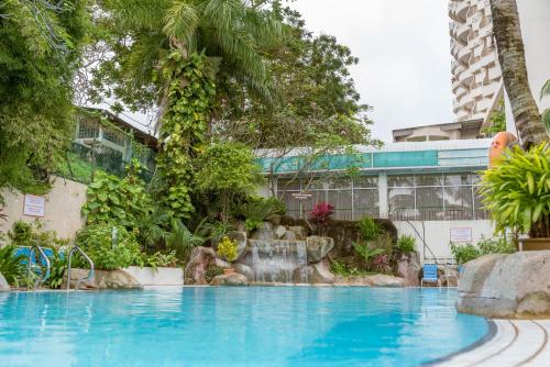 - une piscine dans un complexe avec une cascade dans l'établissement J Beach Suites At Rainbow Paradise, à Tanjung Bungah