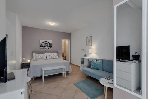 - une chambre avec un lit blanc et un canapé bleu dans l'établissement Apartments Divna, à Baška Voda