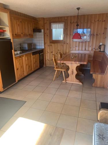 uma cozinha com armários de madeira e uma mesa e cadeiras em Appartement dans chalet em Les Collons