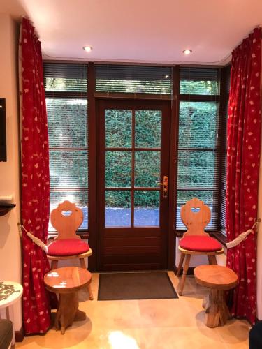 2 chaises avec des coussins rouges assis devant une porte dans l'établissement Romantisch Gastenverblijf 'Het Vogelhuisje', à Lunteren