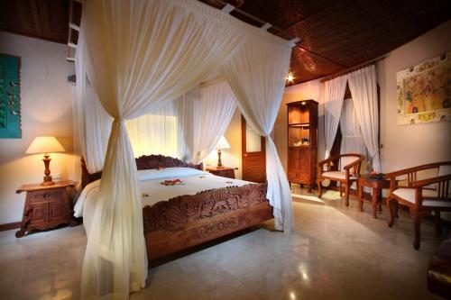 a bedroom with a canopy bed with curtains at Dewani Villa Resort in Canggu