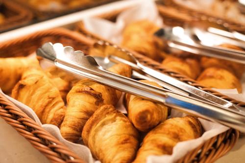 a basket of croissants with tongs on top at Hotel Amberger Hof in Bad Koetzting