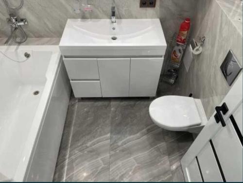 a bathroom with a white sink and a toilet at Lux 1-bedroom Most City Center area in Dnipro