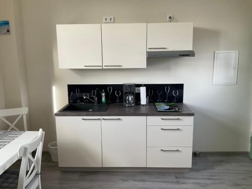 a kitchen with white cabinets and a sink at Ferienwohnung am Froser See in Frose