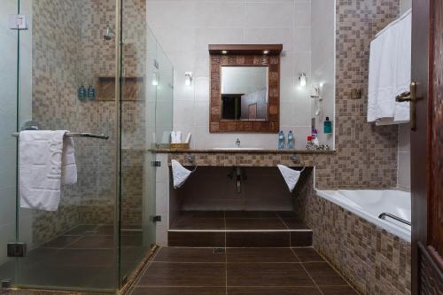 a bathroom with a shower and a sink and a tub at Lake Bogoria Spa Resort in Marigat