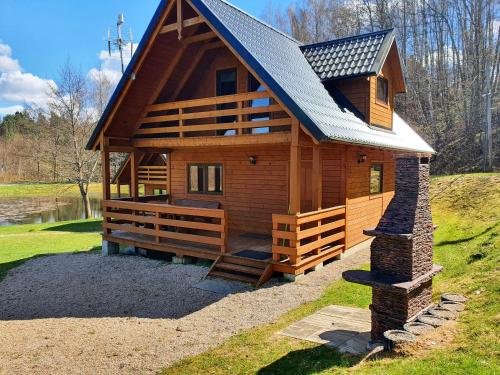 a large wooden cabin with a gambrel roof at Mana Village - Jacuzzi & Sauna in Barłomino