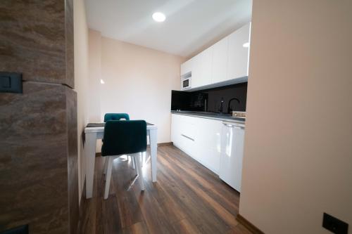 a kitchen with white cabinets and a table with a chair at Luxury Apartments Una Sarajevo in Sarajevo