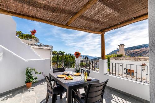 a patio with a table and chairs on a balcony at Apartamentos Entre Senderos in Capileira