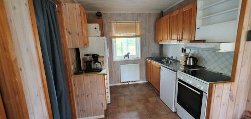 a small kitchen with white appliances and wooden cabinets at Fjällstuga i Foskros m bastu in Idre