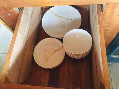 three bowls and plates in a wooden table at Turtles Nest Bunkhouse at Lodge at Long Bay in Corn Island
