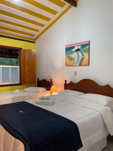 a bedroom with two beds and a painting on the wall at Pousada Valhacouto II in Paraty