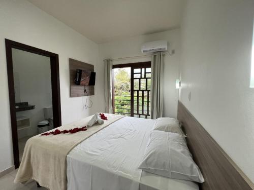 a bedroom with a large white bed with red flowers on it at Pousada Battistella in Garopaba