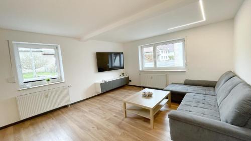 a living room with a couch and a tv at Uraha Apartments Seukendorf in Seukendorf