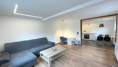 - un salon avec un canapé bleu et une table dans l'établissement Uraha Apartments Seukendorf, à Seukendorf