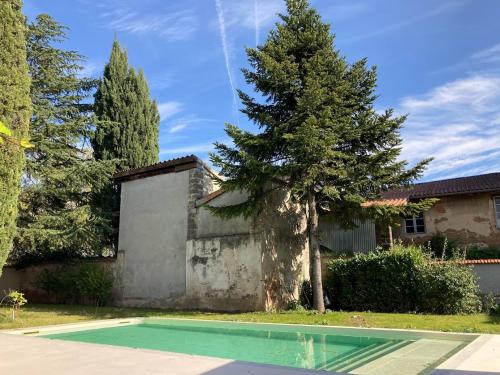 une piscine en face d'une maison avec un arbre dans l'établissement MY BOUTIQUE GUESTHOUSE - Fabulous Suites 10 Min A7 -, à Anneyron