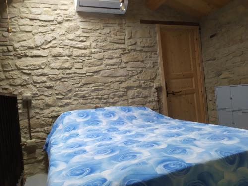 una cama en una habitación con una pared de piedra en Magione Broccoli, en Candelara