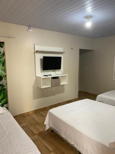a bedroom with two beds and a tv on the wall at Casa Ondas de Alter in Alter do Chao