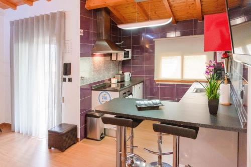 a kitchen with a counter and some purple tiles at Casa da Fonte Gerês in Campo do Gerês