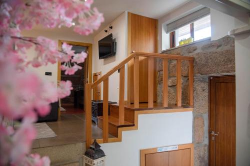 uma escada de madeira numa casa com flores cor-de-rosa em Casa da Fonte em Campo do Gerês