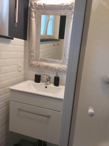 uma casa de banho com um lavatório branco e um espelho. em La Maison de Sidonie em Jalhay