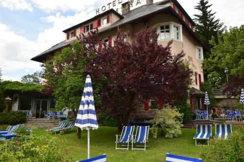 a group of chairs and an umbrella in front of a building at Hotel Villa Emilia in Ortisei