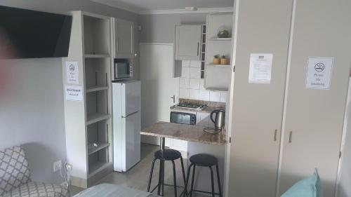 una piccola cucina con bancone e due sgabelli di THE SPARE BEDROOM Unit 2 a Harrismith