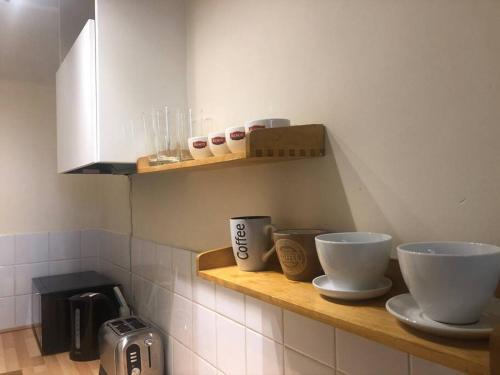a kitchen with two bowls on a wooden shelf at Marcela's Place - Private Studio near Heathrow in West Drayton