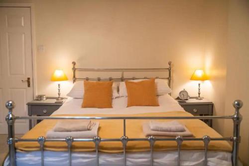 1 dormitorio con 1 cama con almohadas de color naranja y 2 lámparas en The Snug, en Great Malvern