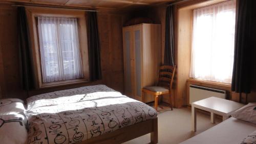 een slaapkamer met een bed, een bureau en 2 ramen bij Apartment Walter in Vals