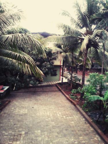 a brick driveway with palm trees in front of a building at Swastik Ac Apartment in Mandrem